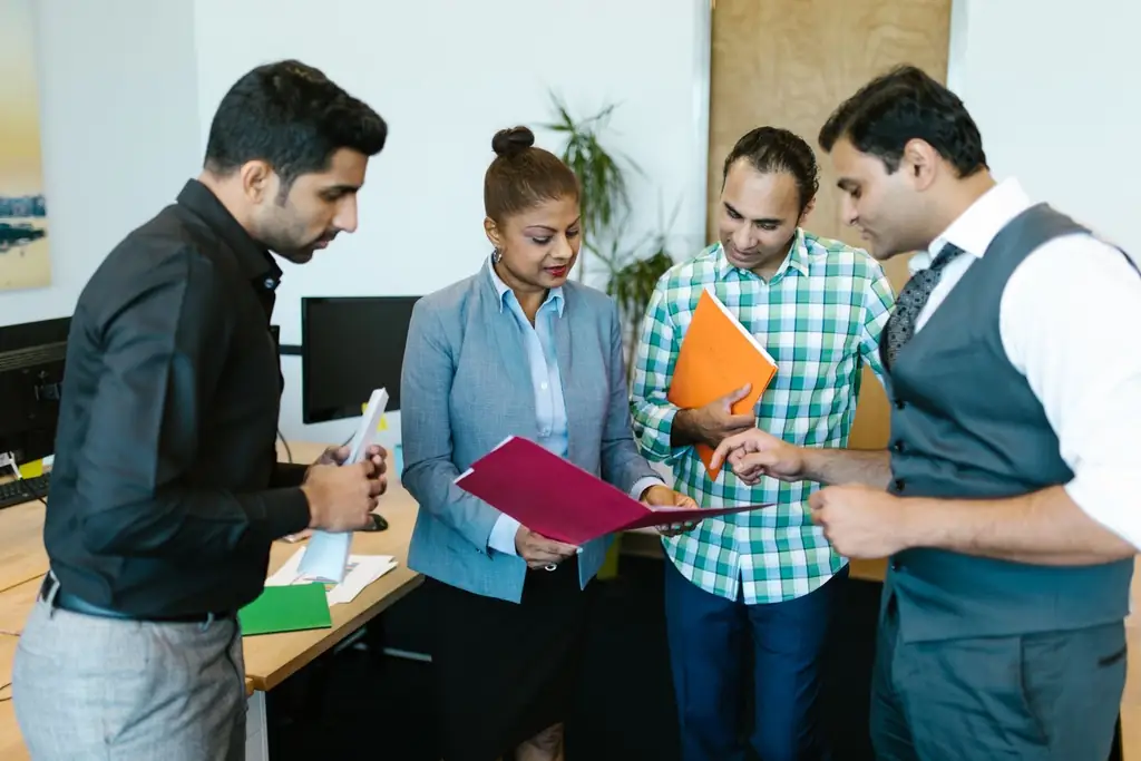 Four colleagues reviewing a document together in a bright office